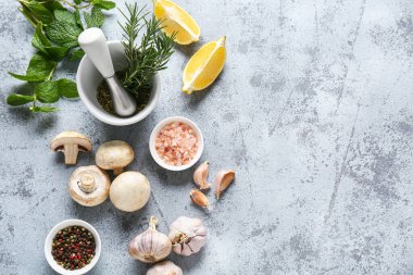 Biberiyeli havan, nane yaprakları ve gri arka planda farklı malzemeler.