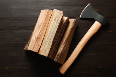 Koyu ahşap arka planda baltalı odun yığınları.