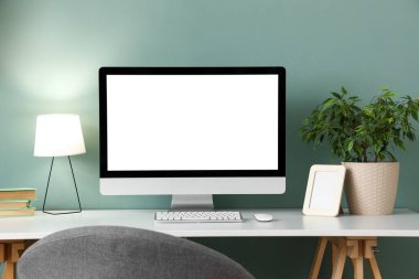 Ofisteki nane duvarının yanında boş bilgisayar monitörü ve parlayan lambası olan işyeri