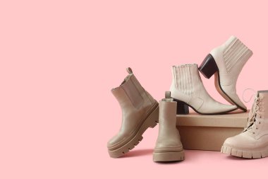 Pembe arka planda ayakkabı kutusu olan kış botları.