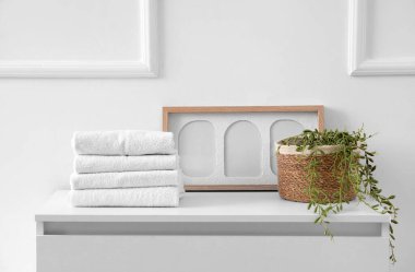 Odadaki aydınlık duvarın yanındaki çekmecelerde çerçeveli ve bitkili temiz havlular.