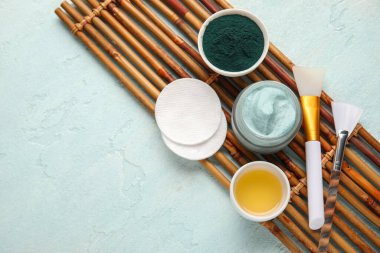 Bambu tepsisi, bir kavanoz spirulina yüz maskesi ve mavi grunge arka planda malzemeleri, yakın plan.