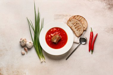 Beyaz zemin üzerinde farklı baharatlar ve ekmek dilimleri olan geleneksel Ukrayna borşundan bir kase