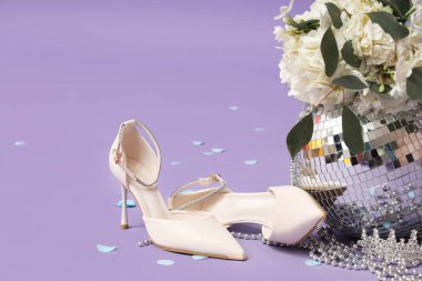 Disko topu, taç ve leylak arka planda çiçekler olan şık topuklu ayakkabılar.