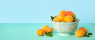 Mavi zemin üzerinde olgun kayısılar ve metin için boşluk olan bir kase