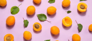 Leylak arka planında bir sürü olgun kayısı ve yeşil yaprak