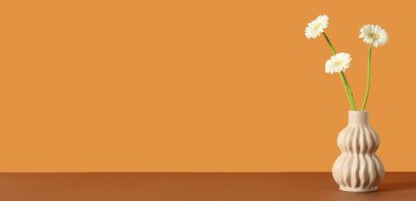 Kahverengi arkaplanda Gerbera çiçekleri ve metin için boşluk olan vazo