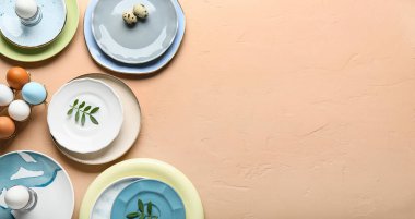 Farklı tabaklar, paskalya yumurtaları ve bej arkaplanda yeşil yapraklar yazı için boşluk, üst görünüm