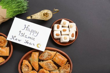 Yazılı kart Mutlu İslami Yeni Yıl, Aladdin lambası ve koyu arkaplanda tatlılar