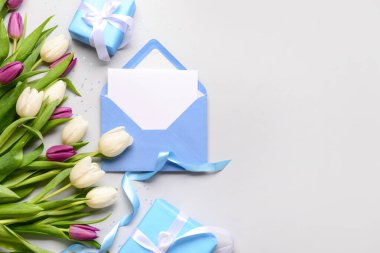 İçinde boş kart, hediye kutuları ve beyaz arka planda lale çiçekleri olan bir zarf. Uluslararası Kadınlar Günü kutlamaları