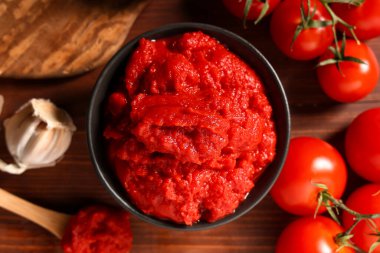 Tahta arka planda sarımsak ve sebzeli bir kase lezzetli domates ezmesi.