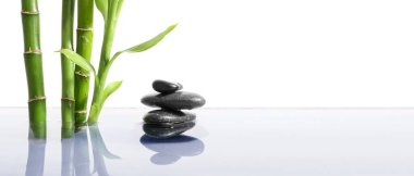 Beyaz arkaplanda beyaz zemin üzerinde suyla spa taşları ve bambu yığını metin için boşluk
