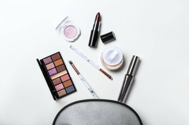 Dekoratif kozmetik ürünleri, makyaj fırçaları ve beyaz arka planda çanta kompozisyonu