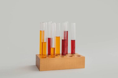 Tahtadan yapılmış renkli numunelerle test tüpleri gri arka planda duruyor.
