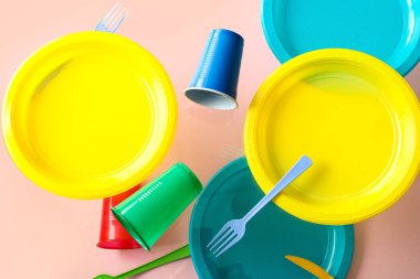 Pembe arka planda renkli plastik sofra takımı havada asılı duruyor