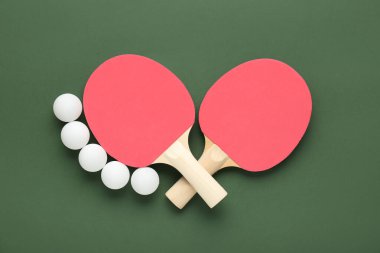 Yeşil arka planda pinpon raketleri ve topları