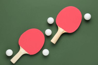 Yeşil arka planda pinpon raketleri ve topları