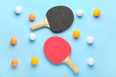 Farklı masa tenisi raketleri ve mavi arkaplanda toplar