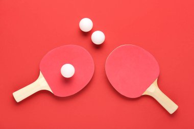 Kırmızı arkaplanda pinpon raketleri ve topları