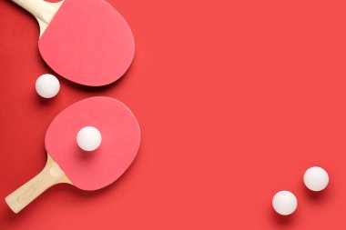 Kırmızı arkaplanda pinpon raketleri ve topları