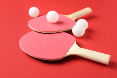 Kırmızı arkaplanda pinpon raketleri ve topları
