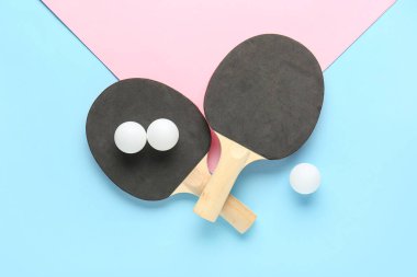 Siyah ping pong raketleri ve renkli arka planda toplar
