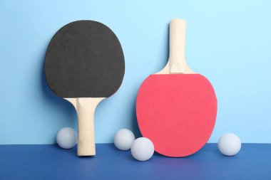 Farklı masa tenisi raketleri ve mavi arkaplanda toplar