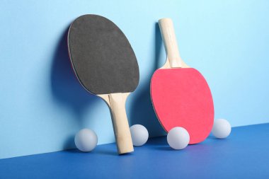 Farklı masa tenisi raketleri ve mavi arkaplanda toplar