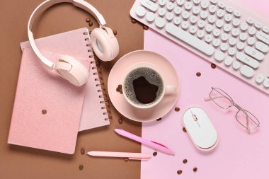 Not defteri, kulaklık, bilgisayar klavyesi, fare ve gözlüklü bir fincan kahve.
