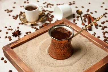 Kumda sıcak Türk kahvesi, gri arka planda fincanlar ve fasulyeler.