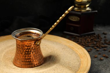 Kumda sıcak Türk kahvesi ve gri arkaplanda fasulye.