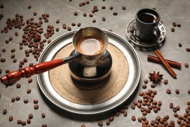 Gri arka planda fincan, baharat ve fasulye ile kumda sıcak Türk kahvesi.