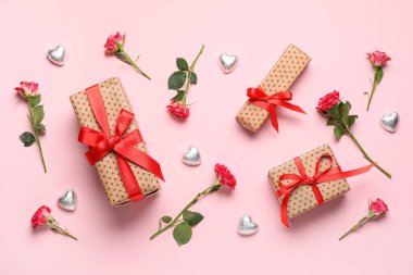 Kalp şeklinde şekerler ve pembe arka planda gül çiçekleri olan hediye kutuları. Sevgililer Günü kutlaması