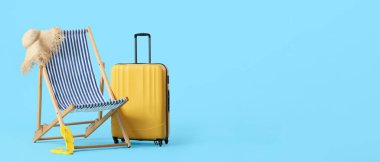 Güverte sandalyesi, hasır şapka, parmak arası terlik ve mavi arka planda mesaj için yeri olan bavul. Turizm konsepti