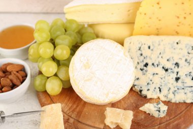 Masada farklı peynir çeşitleri olan ahşap tahta, yakın plan.