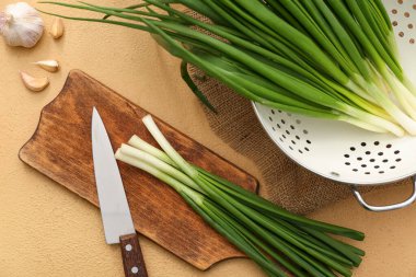 Bej arka planda taze yeşil soğanlı ahşap tahta.