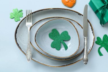 Beautiful table setting for St. Patrick's Day celebration on blue background