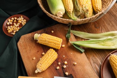 Tahta ve hasır sepette tahtadan yapılmış taze mısır koçanları var.