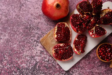 Taze nar ve mor arka planda bir kase tohum.