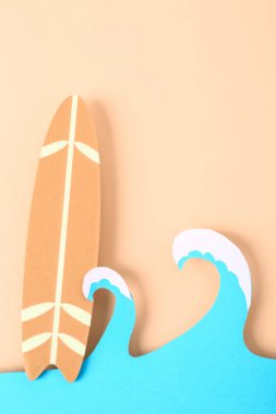 Kağıt dalgaları ve soluk turuncu arka planda mini sörf tahtası olan yaratıcı kompozisyon
