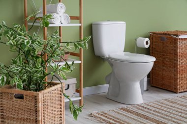 Tuvaletin içinde klozet, raf ünitesi ve sepet var.