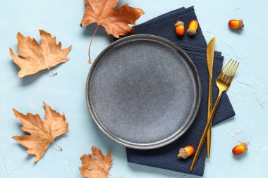 Kuru akçaağaç yaprakları ve mavi arka planda meşe palamudu ile süslü sonbahar masası ayarları