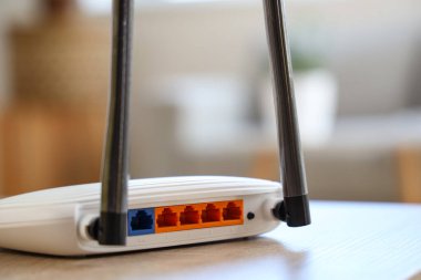 Modern Wi-Fi yönlendirici, oturma odasındaki ahşap masada, yakın plan.