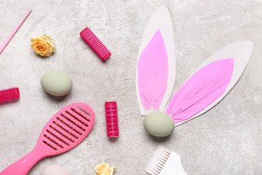 Güllü kuaför aksesuarları, paskalya yumurtaları ve gri grunge arka planda kağıt tavşan kulakları.