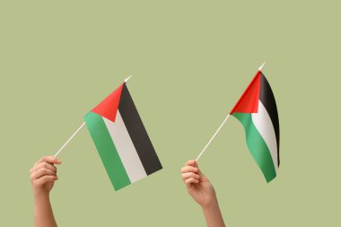 Yeşil arka planda Filistin bayrakları olan kadın eller