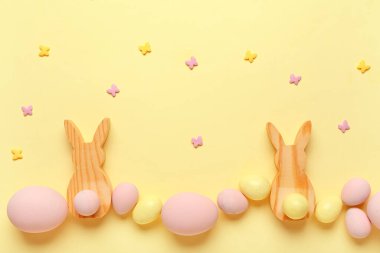 Bej arka planda boyanmış Paskalya yumurtaları ve ahşap tavşanlarla kompozisyon