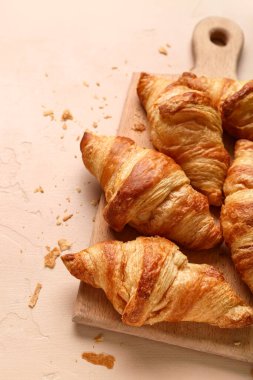 Kahverengi arka planda lezzetli kruvasanları olan ahşap tahta.