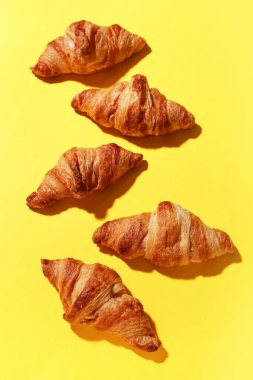 Sarı arka planda bir sürü lezzetli kruvasan.