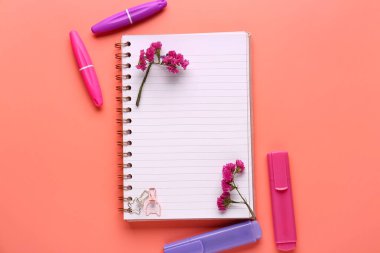 Kırtasiye malzemesi, çiçekler ve pembe arka plandaki defter