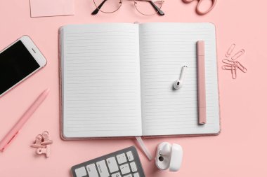 Pembe arka planda defter, telefon ve kalemle kompozisyon. Üst görünüm